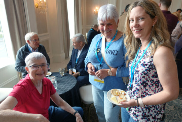 From left to right: Beth Wilson, Pauline Jones, and Heather Hughes. crowd at a reception with food and drinks. Three women looking at the camera.