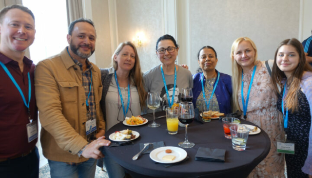Justin Symons, Fouad Bacher, Valerie Phelan, Tanya Vlaskalin, Vani Ranganathan, Donata Chaulk, and Alicja Chaulk. A row of people standing behind a reception table with food and drinks looking at the camera.