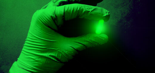 Green radioactive capsule in a gloved hand.