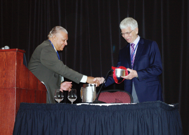 Richard Osborne and Sunil Choubal (CRPA’s longtime archivist) at the CRPA conference in Halifax, NS, in 2012. Two men standing on a stage behind a table and shaking hands. The one on the left (Sunil) appears to be handing something to the one on the right (Richard)
