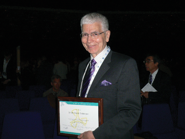 Richard Osborne was the winner of the 2012 Sievert Award. A grey haired man with glasses in a dark suit and tie holding an award plaque
